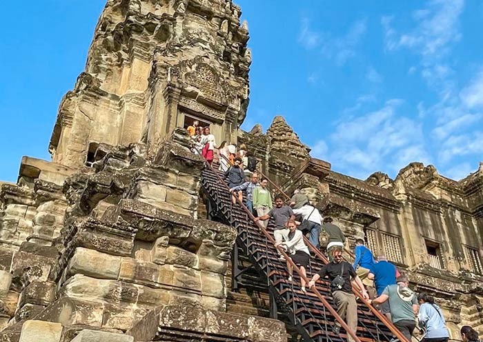Visitors Climbing the Ancient Steps of Angkor Wat